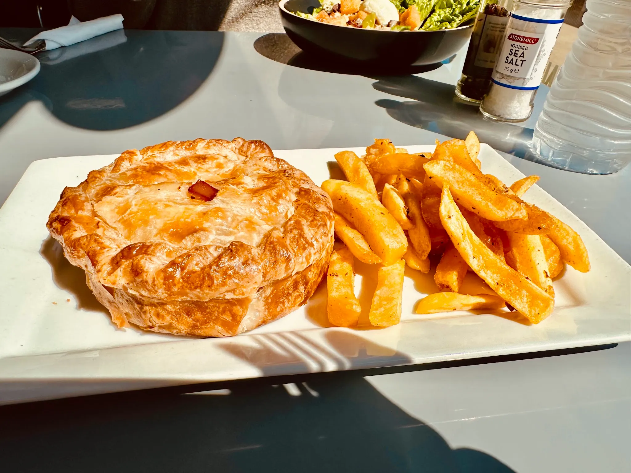 Meat pie and chips on a tray at an outdoor cafe table