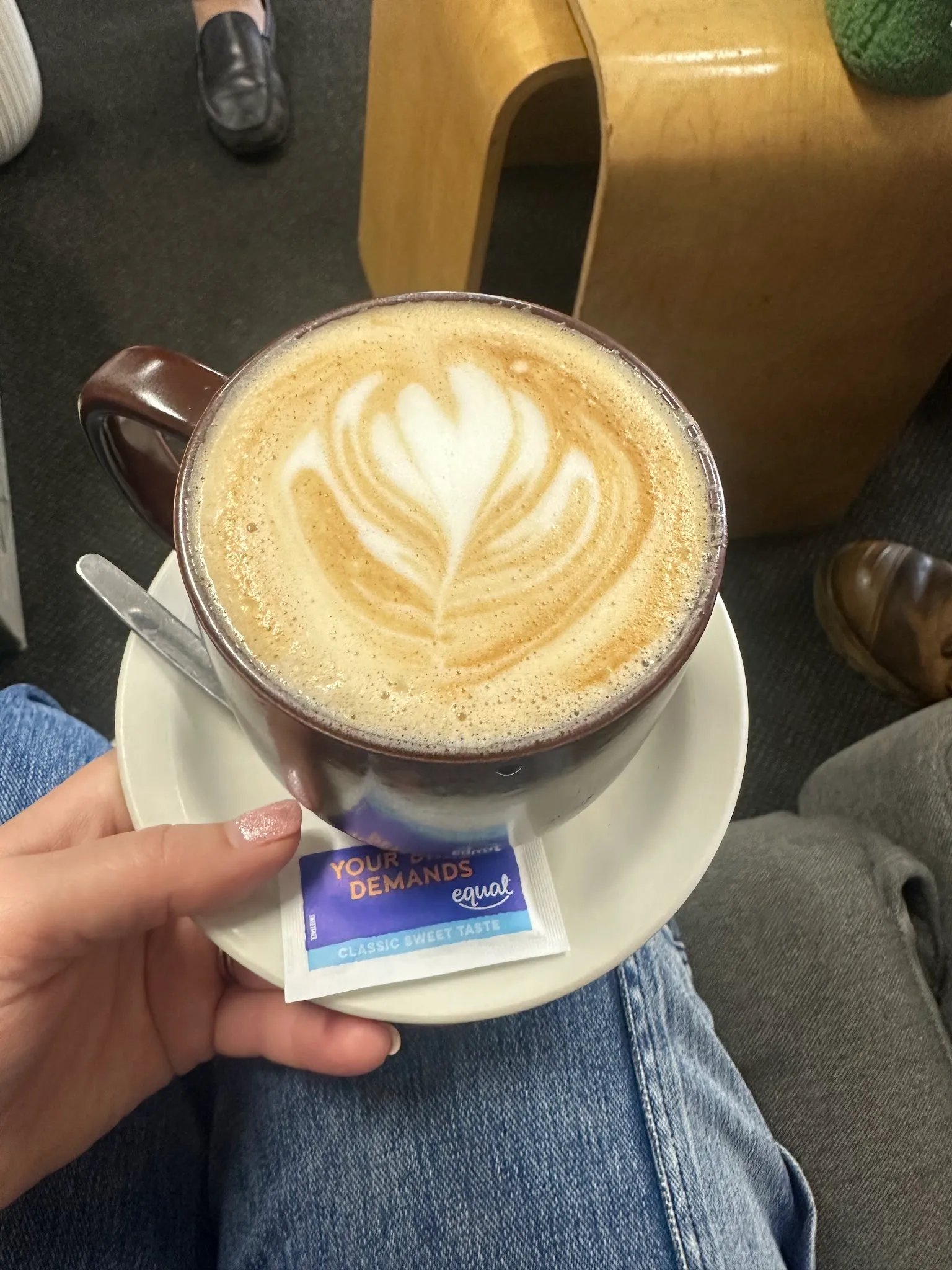 A cup of coffee with latte art, held at a cafe table.