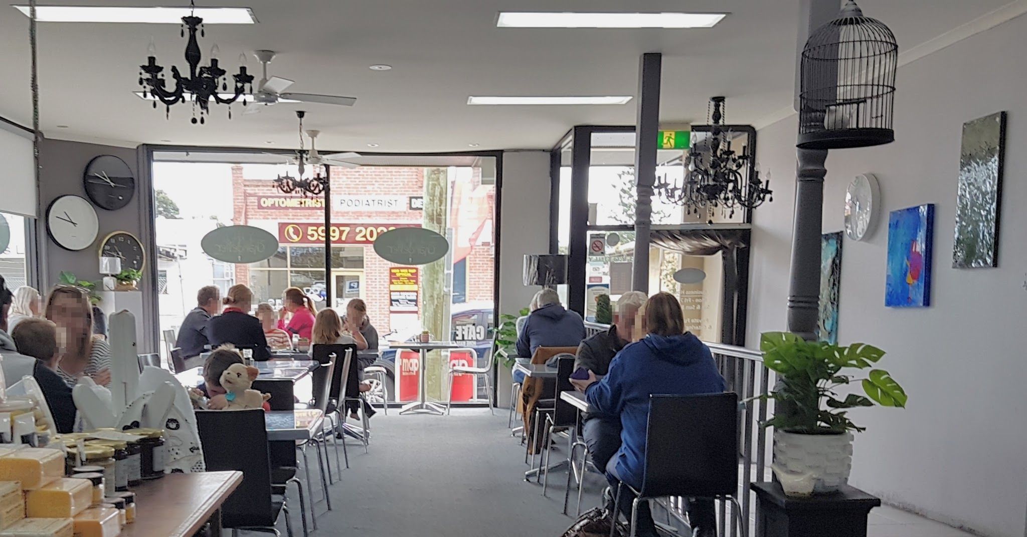 Cafe interior with black chandeliers, birdcage and seated customers